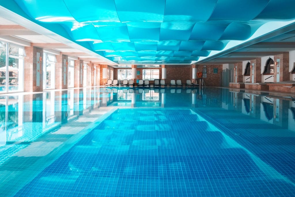 Indoor swimming pool with blue wavy roof. Clear water and calm surface