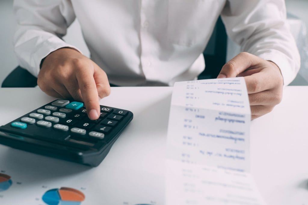 Budgeting concept. Business man using calculator with computer laptop, budget and loan paper in office.