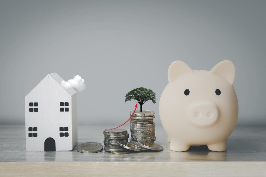 Concept of saving for a house.  Photo of piggy bank and house with stacked coins.