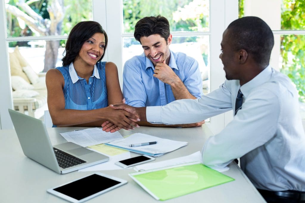 Happy couple shaking hands with real estate agent