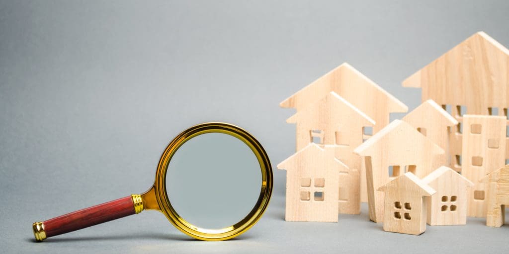 Magnifying glass and wooden houses. House searching concept. 