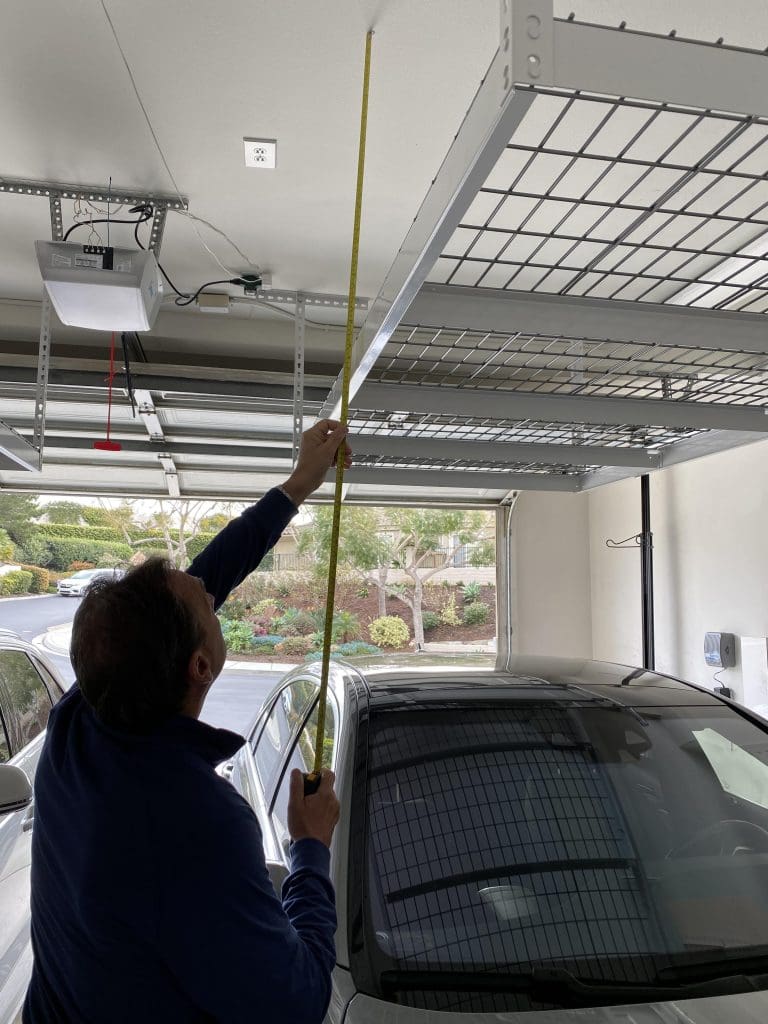 man measuring storage space near garage ceiling.  part of 5 tips to organize your home