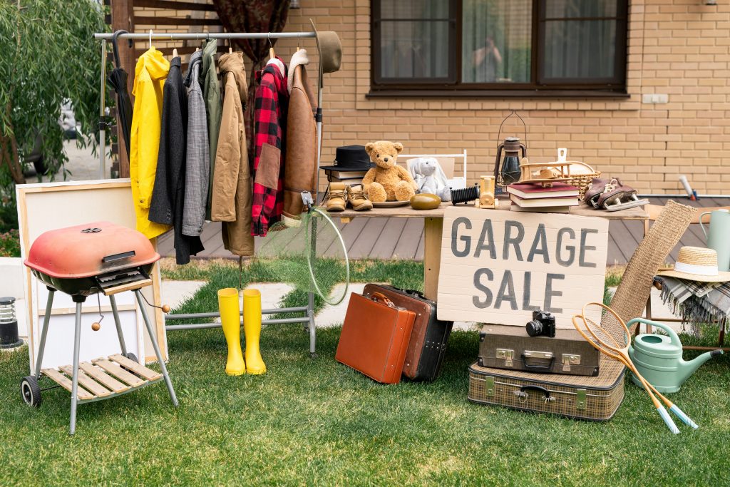 Clothes, sports gear, various household items at a garage sale. 