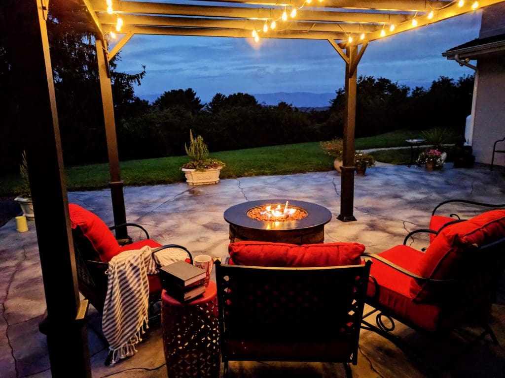 Outdoor living space at night.  Fire pit with chairs around it.  Pergola