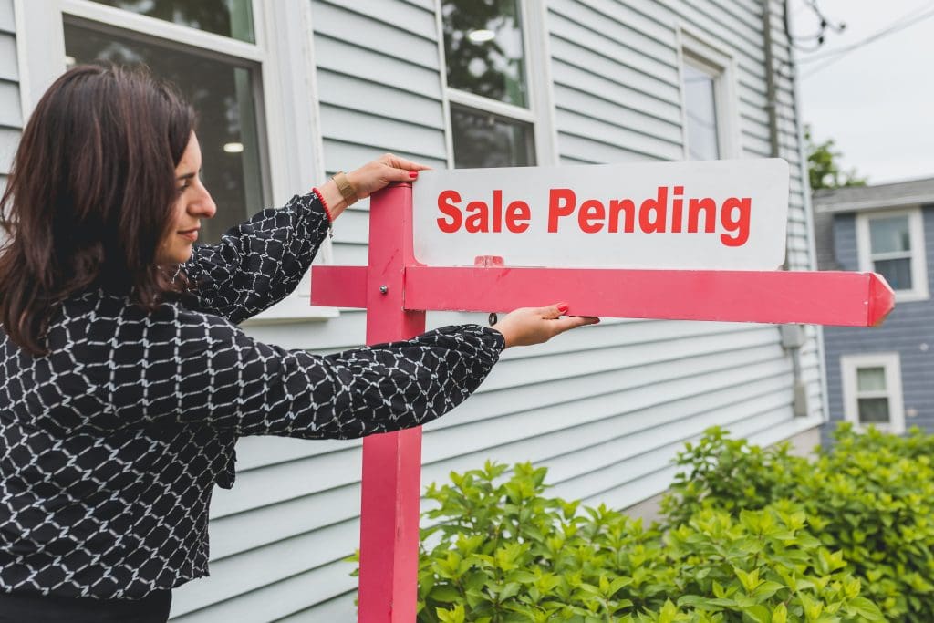 Real estate agent posting a sale pending sign.