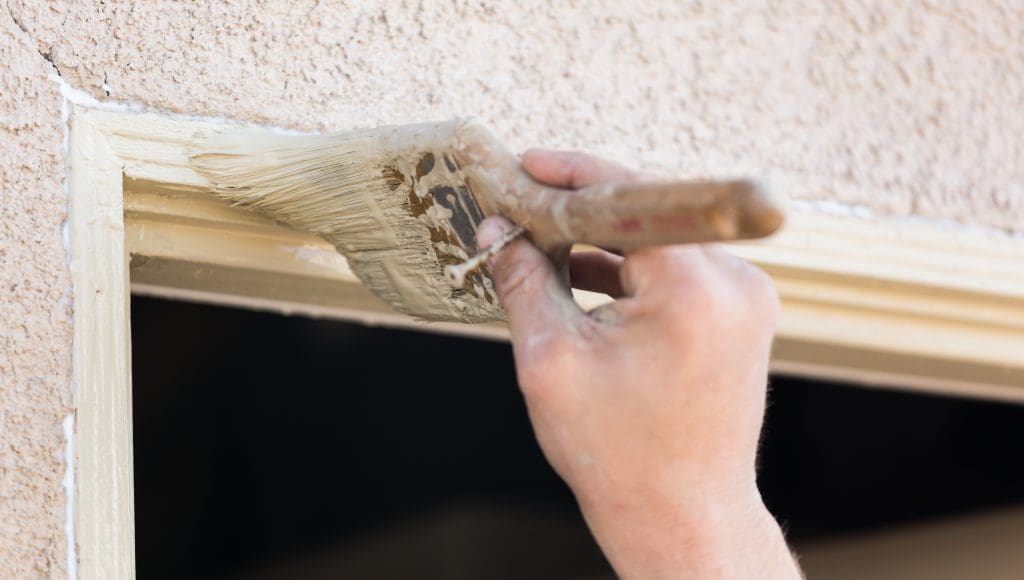 Professional Painter Cutting In With A Brush to Paint House Door Frame.