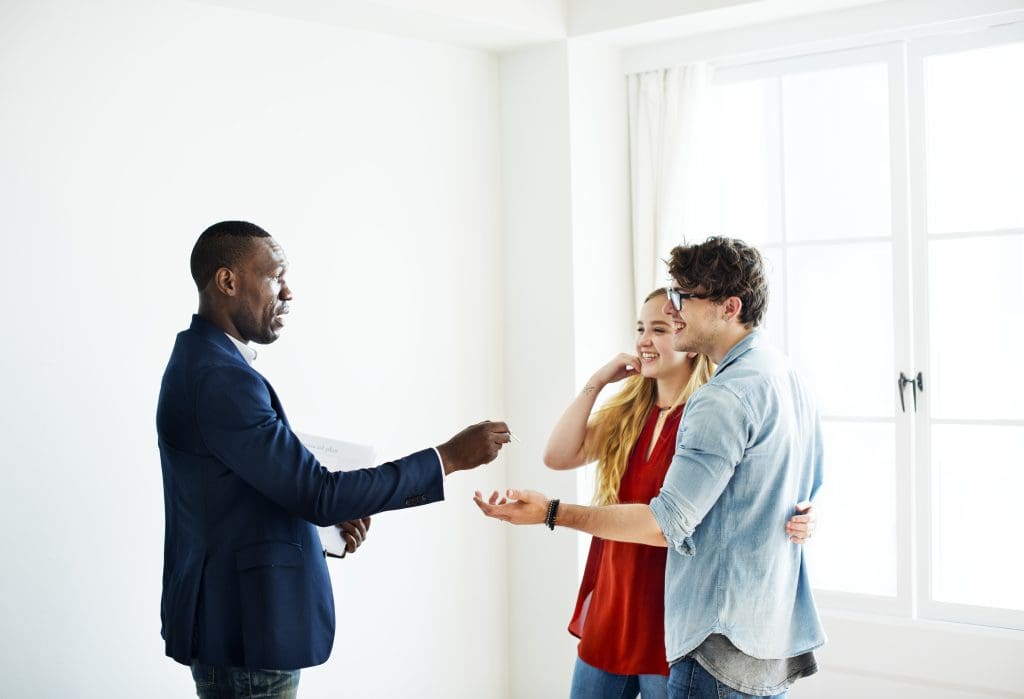 Real estate agent handing the house key to clients