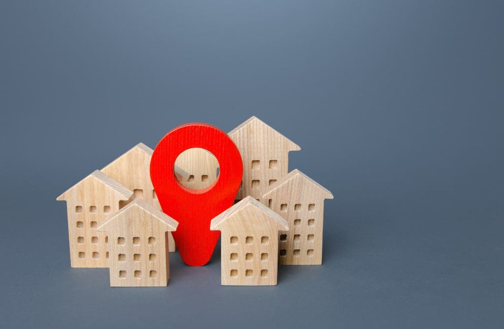 7 Factors That Impact Your Home's Value.  Red location pin and residential buildings. 

