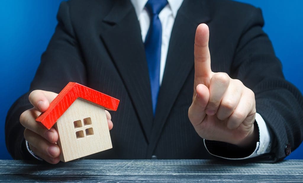 Man with a house makes a gesture of attention. 