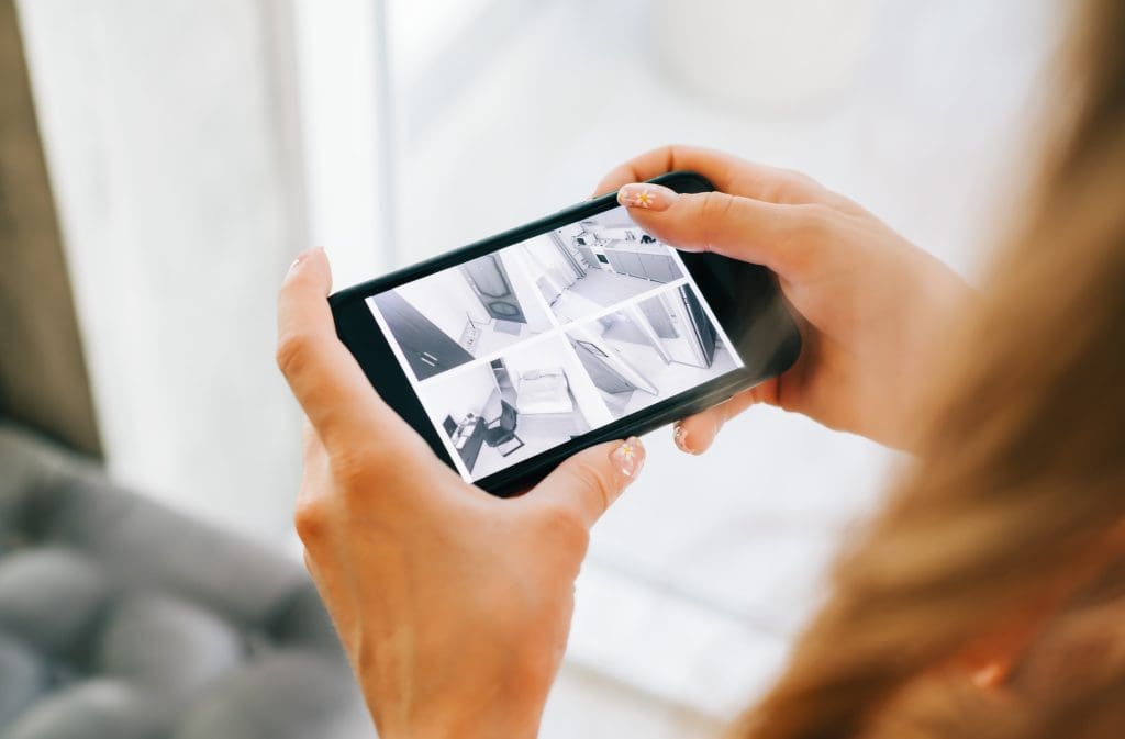 Woman monitoring security cameras on smartphone indoors, closeup.