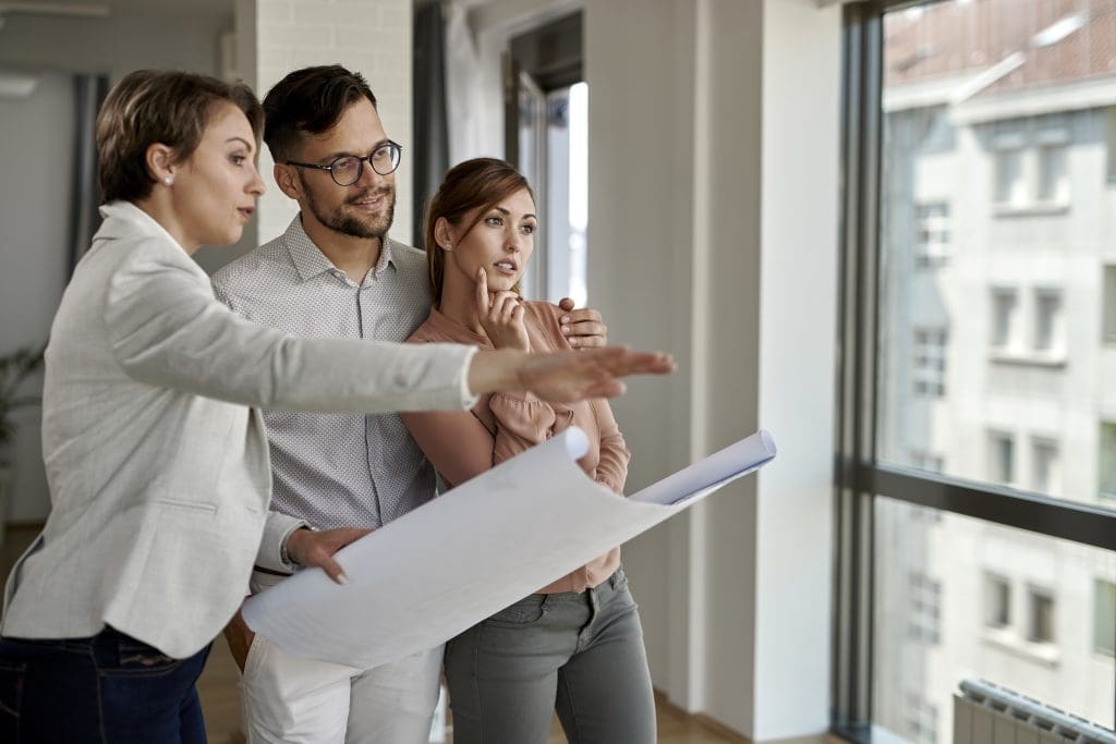 Real estate agent and young couple analyzing housing investment.