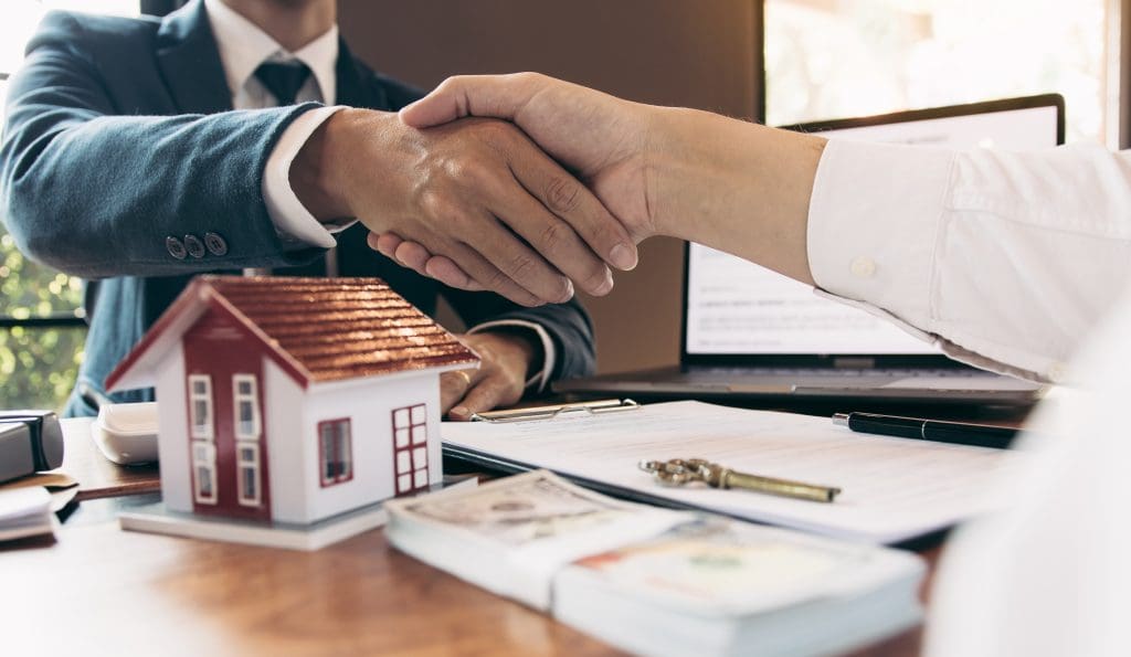 Home sales agents and buyers work on signing new homes and shaking hands.