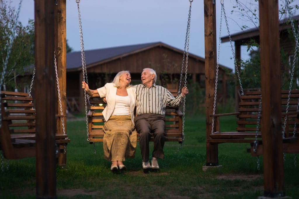 Older couple on porch swing. Man and woman, evening.