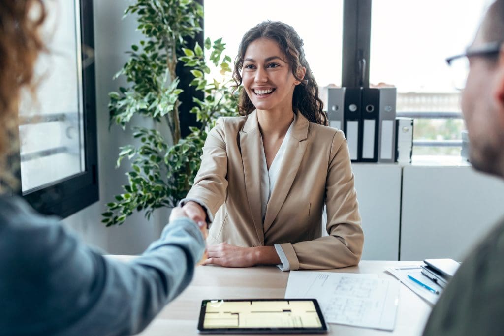 real-estate agent shaking hands with young couple 